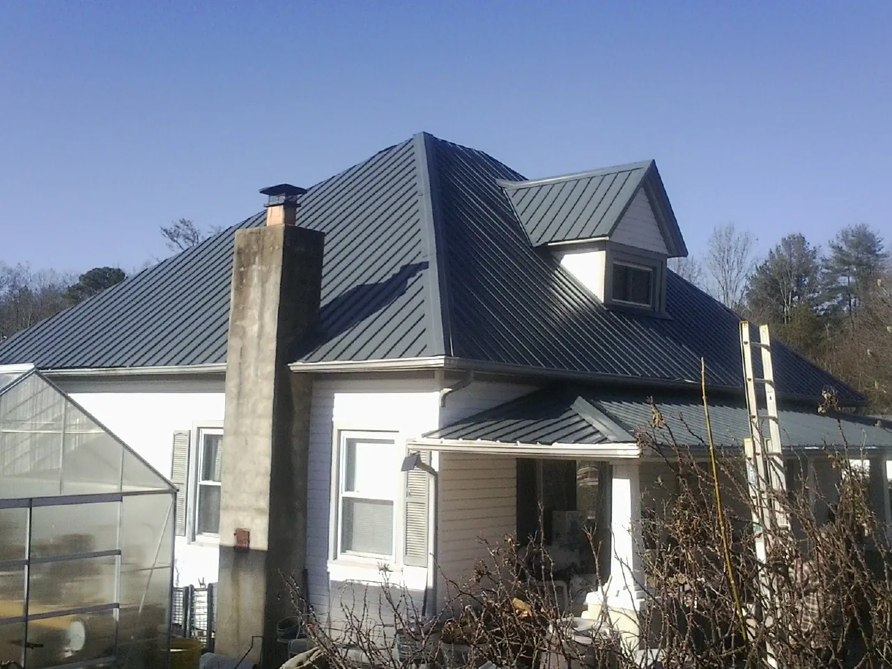 Dark blue standing seam metal roof on a white farmhouse with dormer — Slate & Tile Roof Repair by Roofing Brothers in Wallsburg