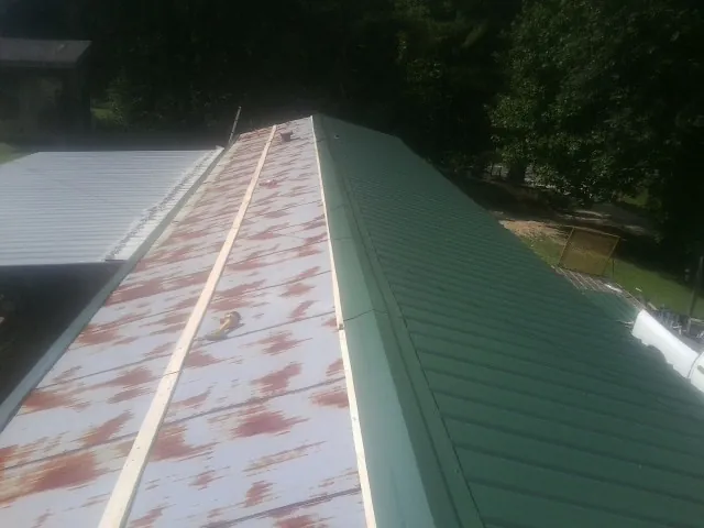 Old rusted panels beside newly installed green metal roofing — Wind Damage Roof Repair by Roofing Brothers in Wallsburg