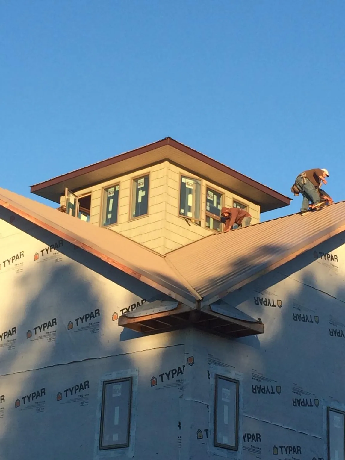 Roofers working around a rooftop cupola on a new metal roof at sunset — Roof Waterproofing in Wallsburg by Roofing Brothers